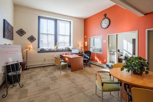 A whiteboard in a room with orange walls and a table with chairs.