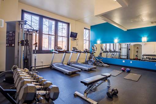 A gym with a variety of equipment including treadmills, dumbbells, and weight machines.