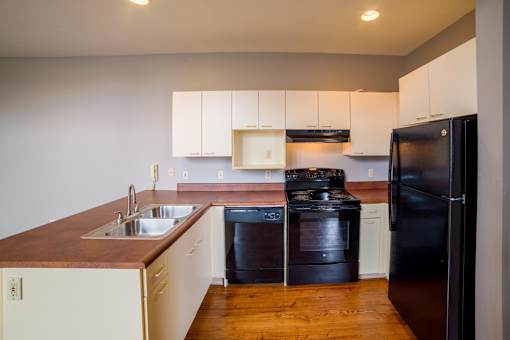 A kitchen with black appliances and wooden countertops.