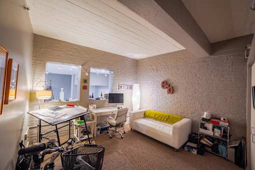 A room with a white couch and a desk with a computer.