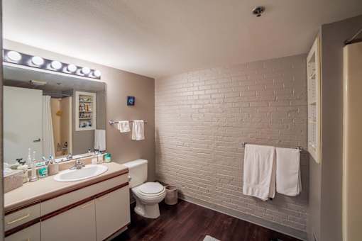A bathroom with a white brick wall and a toilet.