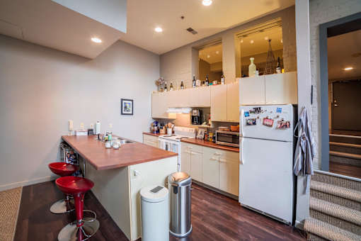 A kitchen with white appliances and a red bar stool.