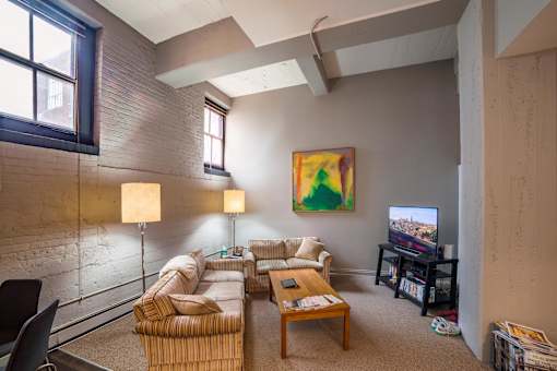 A living room with a couch, chair, and a painting on the wall.