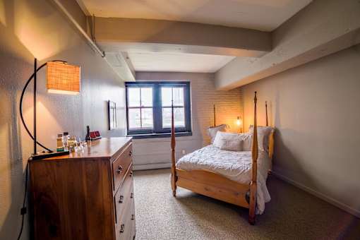 A bedroom with a bed, dresser, and window.