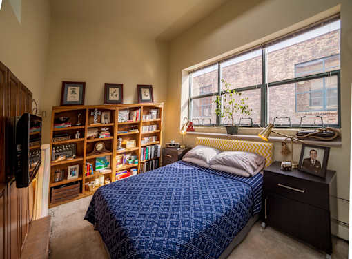 A bedroom with a bed, nightstand, and bookshelf.