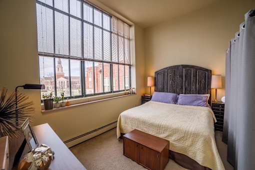 A bedroom with a large bed and a window overlooking a cityscape.