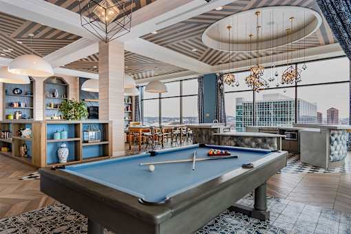 A pool table is in the middle of a room with a view of the city.