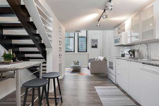 A modern kitchen with white cabinets and a wooden floor.
