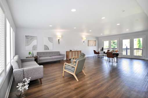 A living room with a grey couch, a wooden chair, and a grey sofa.