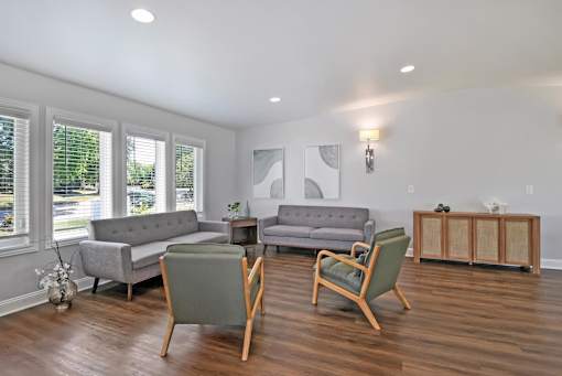 A living room with a grey couch, a green armchair, and a wooden table.