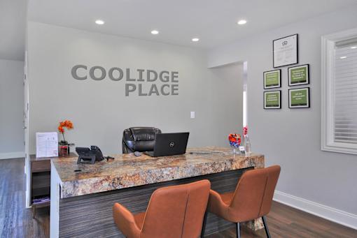 A reception area with a marble counter and chairs.