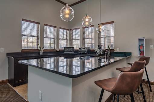 A kitchen with a black countertop and brown chairs.