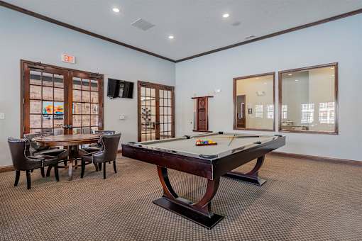 A room with a pool table and a table with chairs.