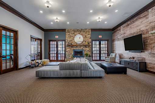 A large bedroom with a stone fireplace and a flat screen TV mounted on the brick wall.
