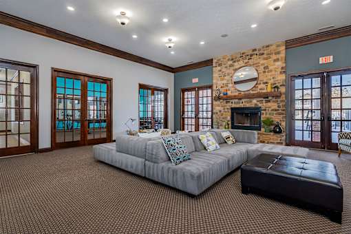 A living room with a grey couch and a stone fireplace.