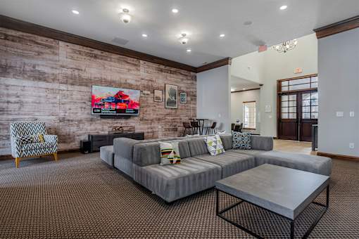 A living room with a grey couch and a wooden wall.
