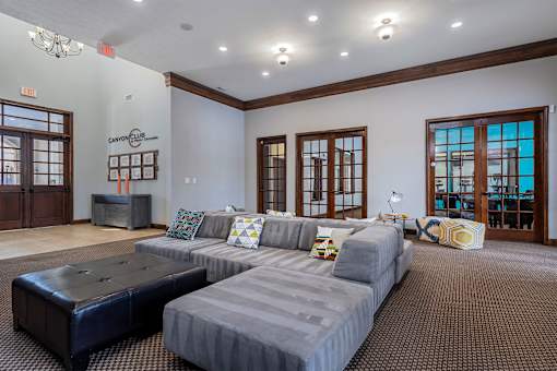 A living room with a grey couch and a black ottoman.