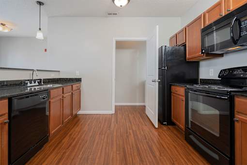 A kitchen with black appliances and wooden cabinets.