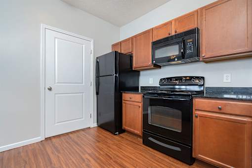 A kitchen with black appliances and wooden cabinets.
