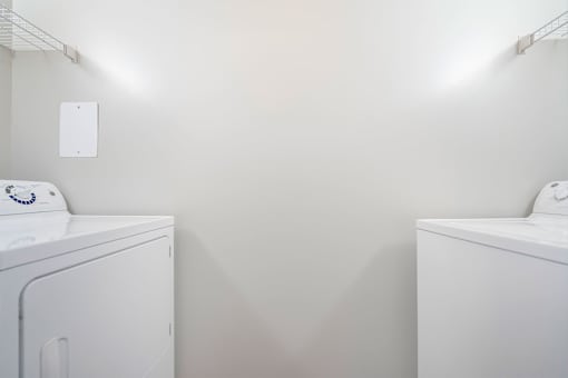Two white washing machines in a laundry room.