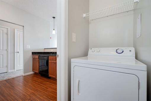 A white washing machine sits in a kitchen next to a white door.