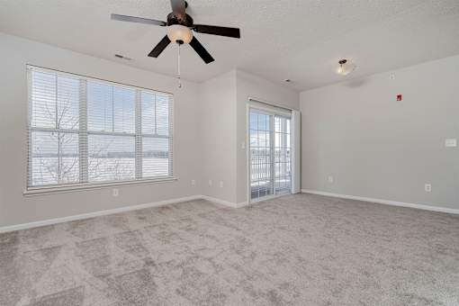 A room with a ceiling fan and carpeted floor.