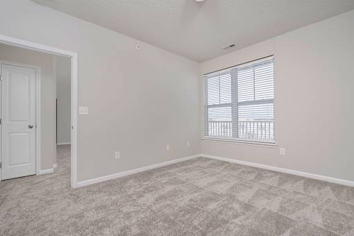 A room with a carpeted floor and a window with blinds.