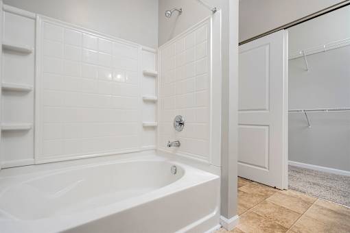 A white bathroom with a tub and a walk in shower.