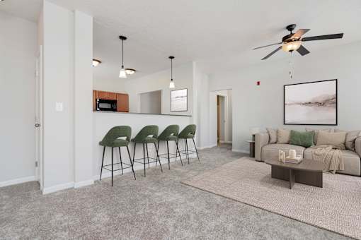 A living room with a grey sofa, green chairs, and a ceiling fan.