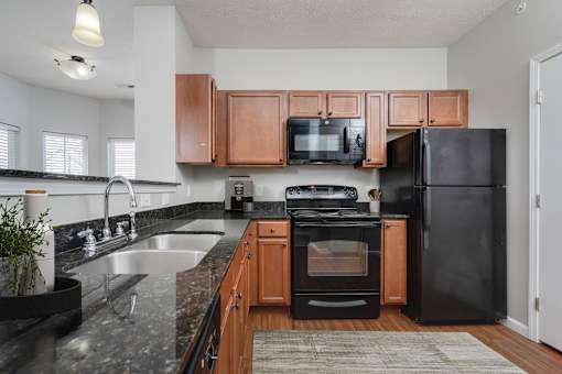 A kitchen with black appliances and wooden cabinets.
