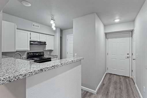 A kitchen with a granite countertop and white cabinets.