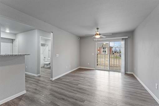 A spacious room with a sliding glass door leading to a balcony.