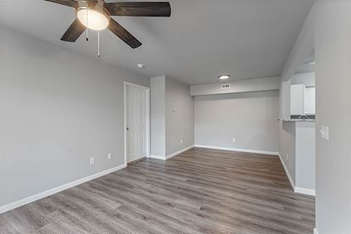 A room with a ceiling fan and wooden flooring.