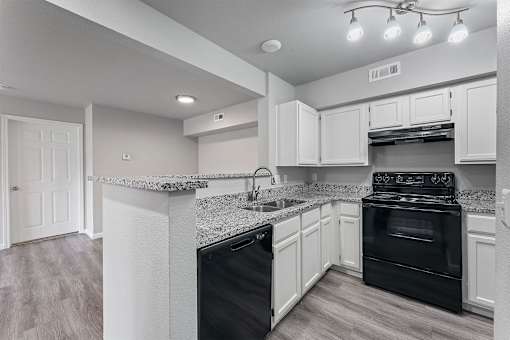 A kitchen with black appliances and white cabinets.