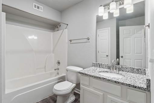 A white bathroom with a toilet, sink, and bathtub.