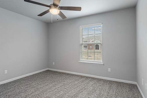 A room with a ceiling fan and a window with blinds.