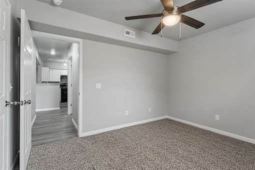 A room with a ceiling fan and a door leading to another room.