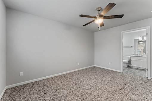 A room with a ceiling fan and carpeted floor.
