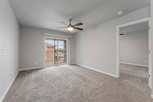 A spacious room with a ceiling fan and a door leading to a balcony.