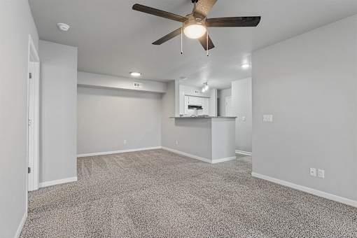 A room with a ceiling fan and carpeted floor.