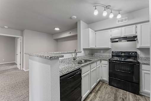 A kitchen with black appliances and white cabinets.