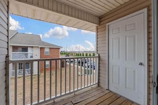 A white door is open to a deck with a railing.