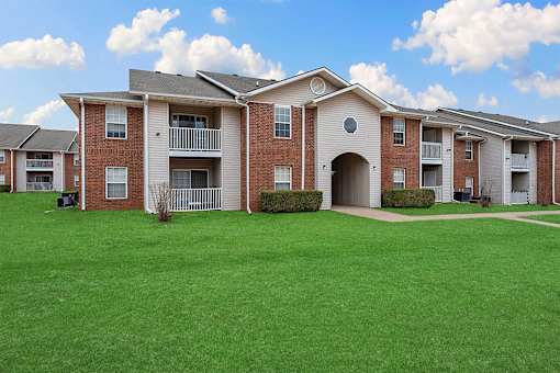 Apartment complex with red brick buildings and green lawns.