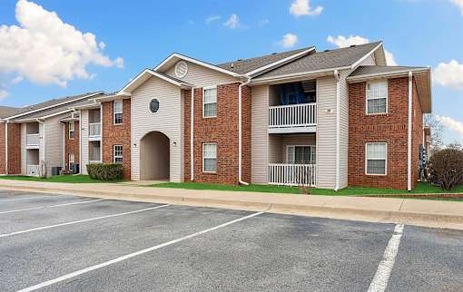 Apartment building with a parking lot in front.