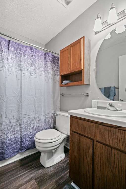 A white toilet sits next to a wooden cabinet in a bathroom.