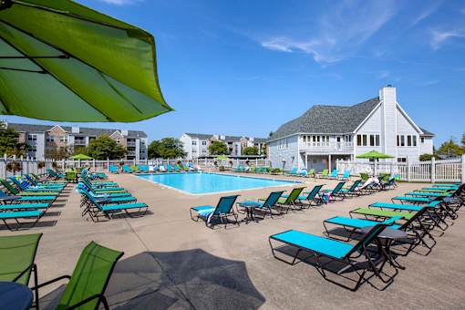 A pool surrounded by lawn chairs and umbrellas.