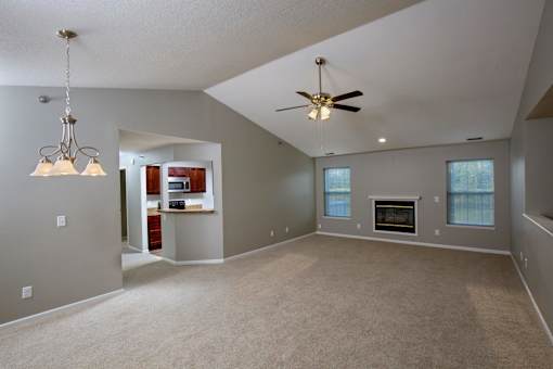 A spacious living room with a fireplace and a ceiling fan.
