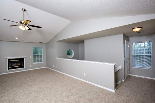 A spacious living room with a fireplace and a ceiling fan.