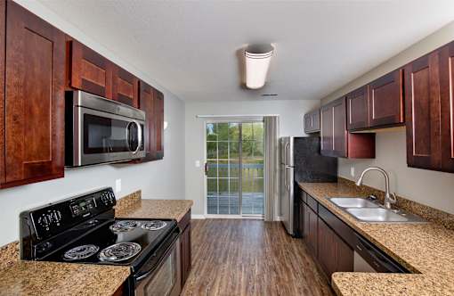 A kitchen with a black stove top oven and wooden cabinets.