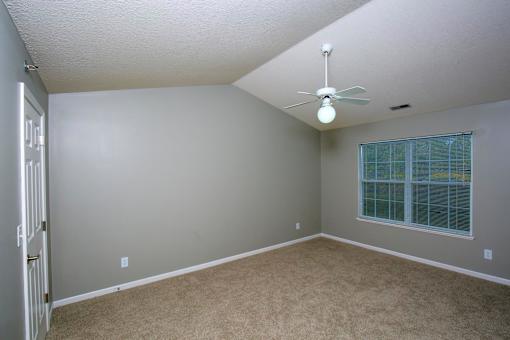 A room with a ceiling fan and a window with blinds.